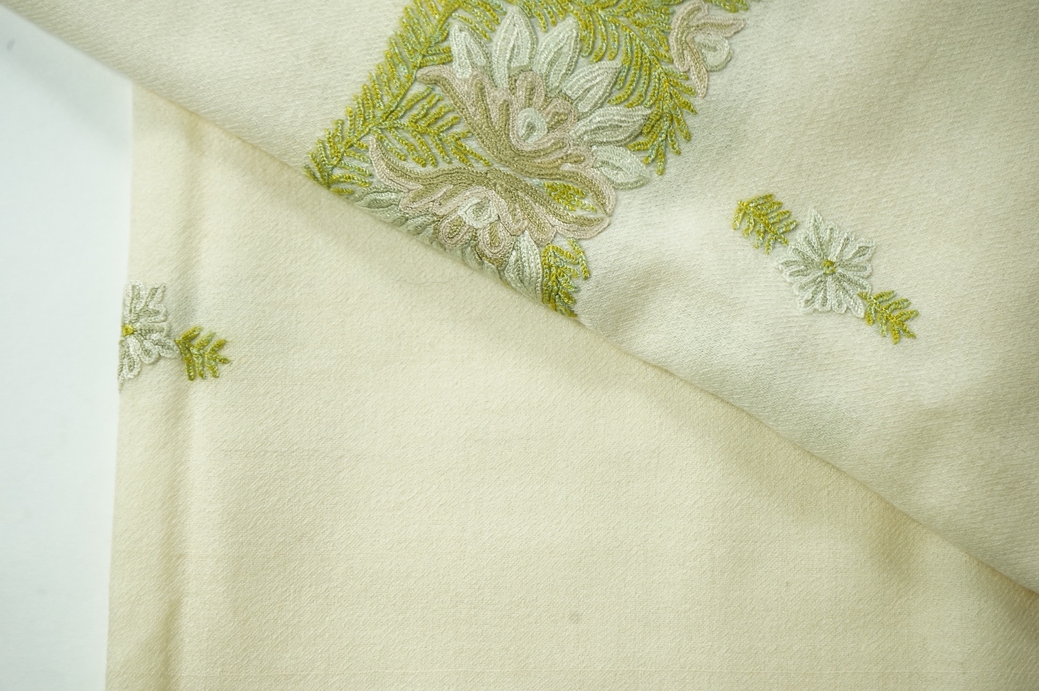 An Indian green and gold silk hand woven brocade stole, a cream pashmina embroidered stole and a similar finely woven and embroidered lilac stole (3). Brocade stole 38cm x 180cm., Condition - light stain to finely woven